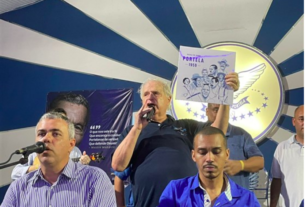 Presidente da Portela Luis Carlos Magalhães presta homenagem a Mestre Monarco no palco da quadra da escola segurando um LP