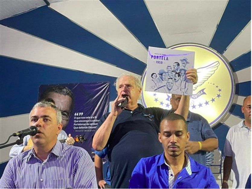 Presidente da Portela Luis Carlos Magalhães presta homenagem a Mestre Monarco no palco da quadra da escola segurando um LP